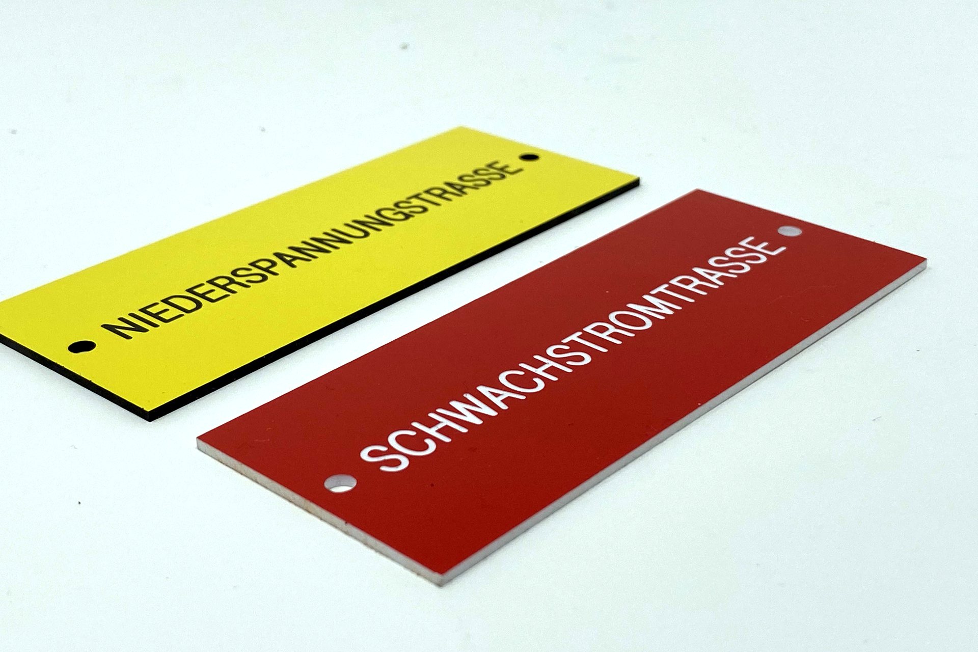 Zwei gravierte Kunststoffschilder in Gelb und Rot mit Warnbeschriftung